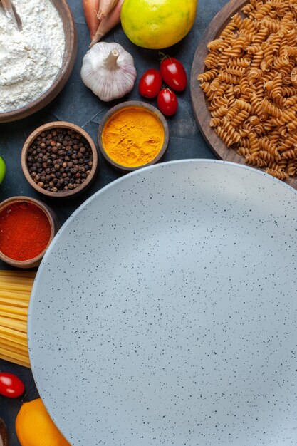 Vue de dessus assiette vide autour des assaisonnements de tomates oeufs et pâtes italiennes sur fond sombre couleur cuisine de légumes nourriture repas de fruits