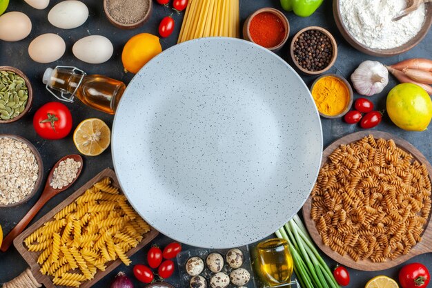 Vue de dessus assiette vide autour des oeufs tomates assaisonnements et pâtes italiennes sur fond sombre couleur nourriture repas cuisine cuisine fruits