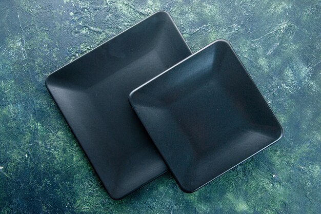 Vue de dessus assiettes carrées noires sur fond sombre dîner restaurant cuisine couleur couverts cuisine obscurité utencil