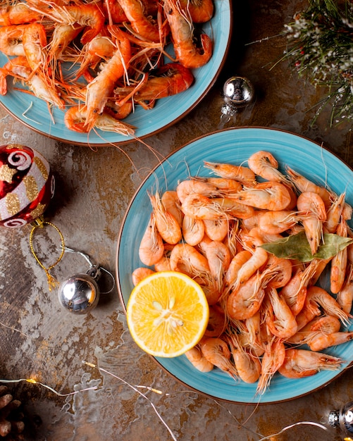 Vue de dessus des assiettes de crevettes servies avec des citrons