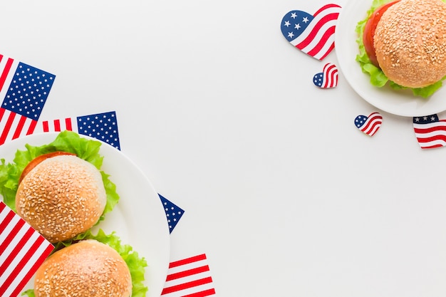 Vue de dessus des assiettes avec des drapeaux américains et des hamburgers