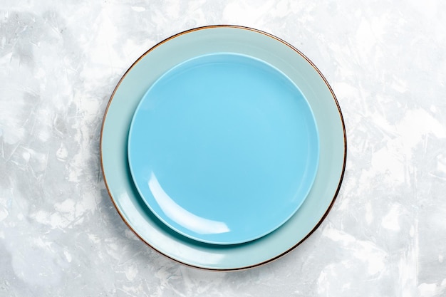 Vue de dessus des assiettes rondes vides bleues sur une surface blanche