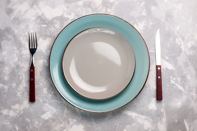 Photo gratuite vue de dessus des assiettes vides en verre avec fourchette et couteau sur une surface blanche