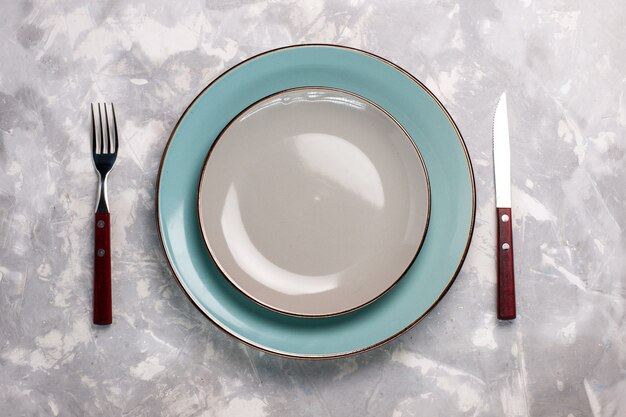 Vue de dessus des assiettes vides en verre avec fourchette et couteau sur une surface blanche