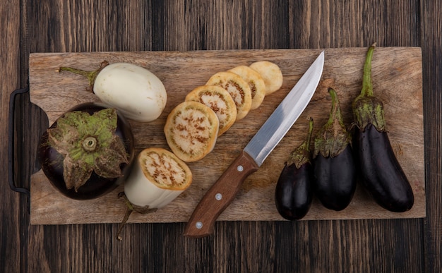 Vue de dessus aubergine blanche en tranches et noir avec un couteau sur une planche à découper sur fond de bois