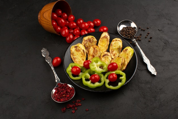 Vue de dessus d'aubergines cuites avec des poivrons verts tranchés et des tomates rouges entières sur le bureau sombre