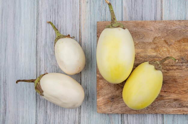 Vue de dessus d'aubergines jaunes et blanches sur une planche à découper sur fond de bois