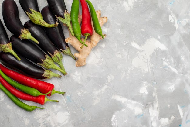 Vue de dessus aubergines noires avec des poivrons sur le bureau lumineux repas de légumes frais crus