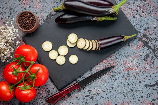 Vue de dessus aubergines noires avec des tomates rouges fraîches sur la surface bleue cultiver des aliments dîner couleur arbre salade de repas photo