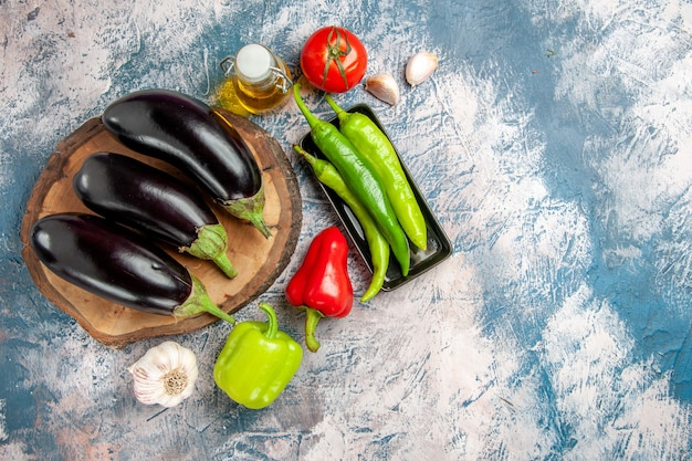 Vue de dessus aubergines sur planche de bois d'arbre piments forts sur plaque noire