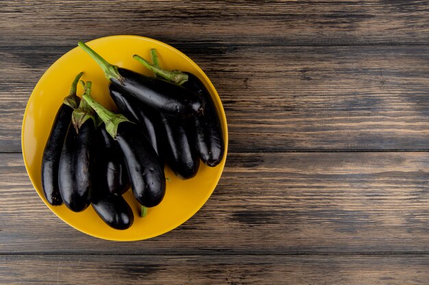 Vue de dessus des aubergines en plaque sur le côté gauche et fond en bois avec copie espace