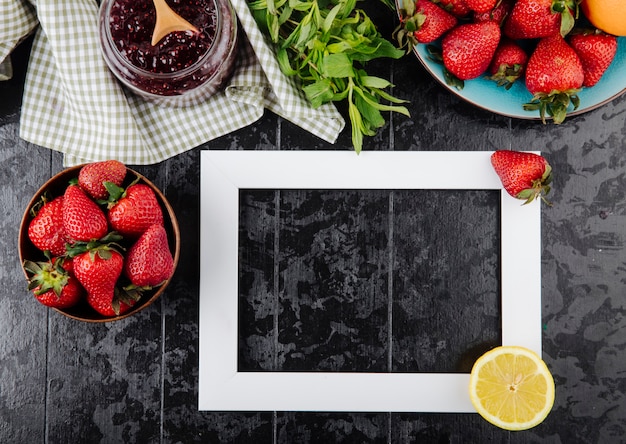 Vue de dessus aux fraises avec de la confiture de fraises à la menthe et une tranche de citron sur fond noir