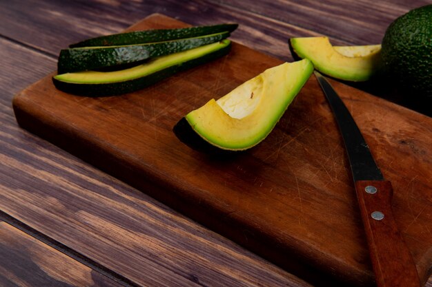 Vue de dessus avocat en tranches avec un couteau sur une planche à découper sur une table en bois