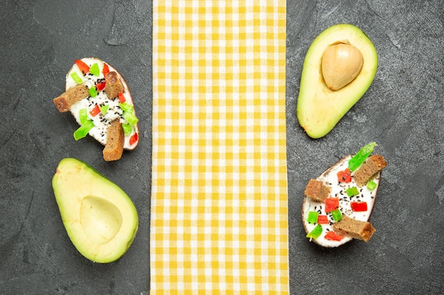 Vue de dessus des avocats crémeux avec du pain et du poivre sur une surface gris foncé