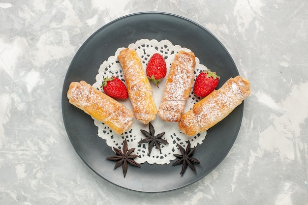 Vue de dessus des bagels en poudre de sucre pâte délicieuse avec des fraises sur une surface blanche