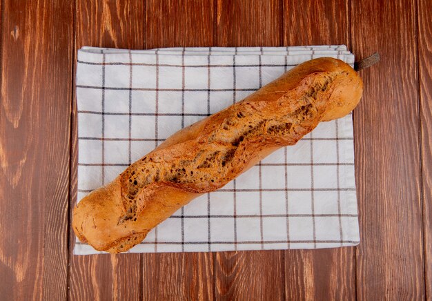 Vue de dessus de la baguette noire sur tissu à carreaux et fond en bois