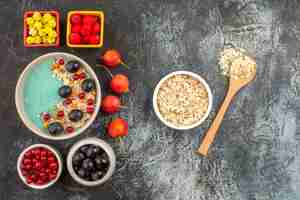 Photo gratuite vue de dessus des baies groseilles rouges raisins noirs baies colorées bol de cuillère en bois à l'avoine