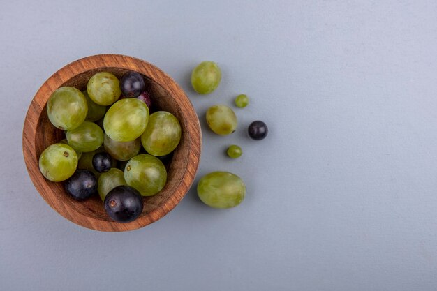 Vue de dessus des baies de raisin dans un bol et sur fond gris avec espace copie