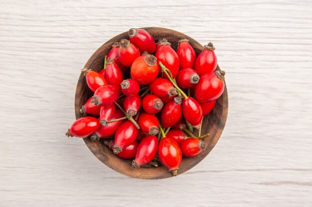 Vue de dessus des baies rouges fraîches à l'intérieur de la petite assiette sur fond blanc