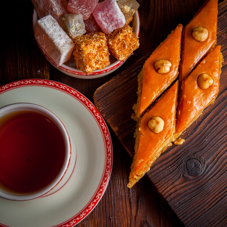 Photo gratuit vue de dessus baklava avec tasse de thé et délice turc en planche de bois
