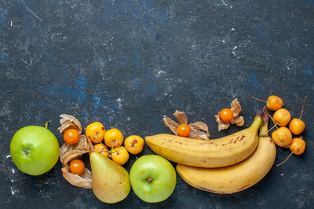 Vue de dessus bananes jaunes paire de baies avec des pommes vertes fraîches poires cerises douces sur le bureau bleu foncé fruits baies santé vitamine