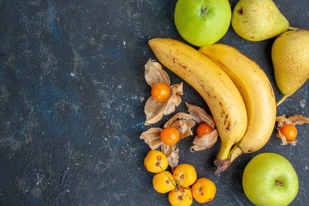 Vue de dessus bananes jaunes paire de baies avec des pommes vertes poires sur le fond bleu foncé baies de fruits frais santé vitamine