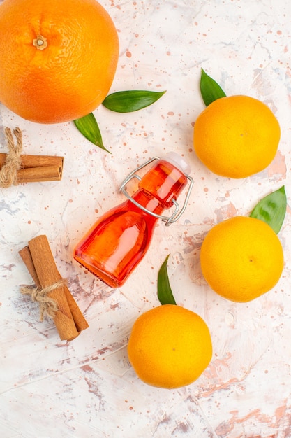 Photo gratuite vue de dessus des bâtons de cannelle mandarines fraîches bouteille orange sur une surface lumineuse