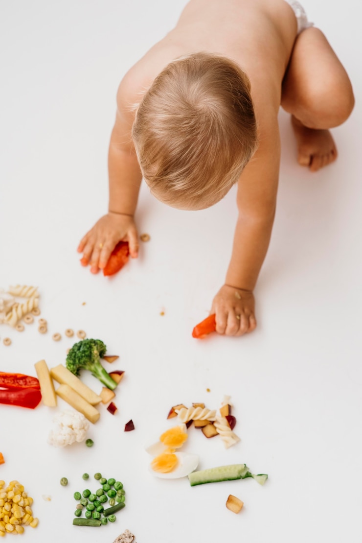 Photo gratuit vue de dessus bébé en choisissant quoi manger seul