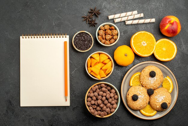 Vue de dessus des biscuits au sable avec des tranches d'orange sur une surface gris foncé gâteau au thé aux biscuits aux fruits sucrés