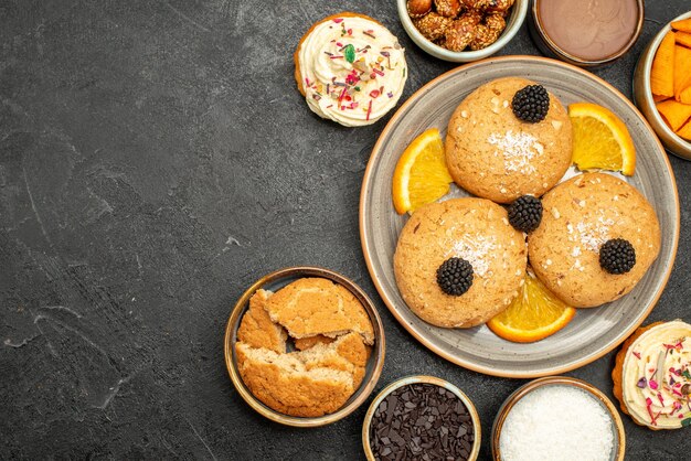 Vue de dessus des biscuits au sucre avec des tranches d'orange sur une surface sombre biscuits biscuit gâteau au thé sucré