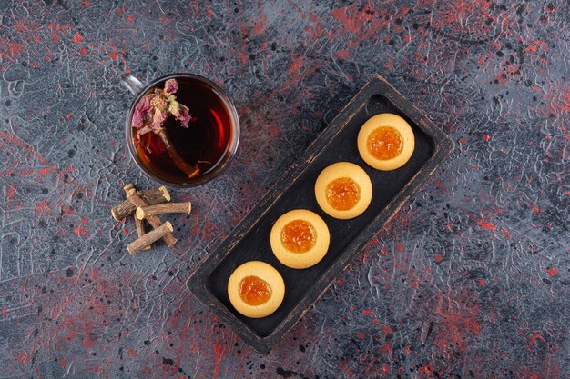 Vue de dessus des biscuits à la confiture fraîche avec du thé parfumé sur rustique.