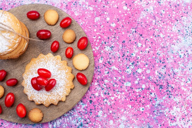 Vue de dessus de biscuits sandwich crémeux avec cornouiller rouge frais et aigre sur lumineux, biscuit gâteau biscuit aux fruits aigre-douce