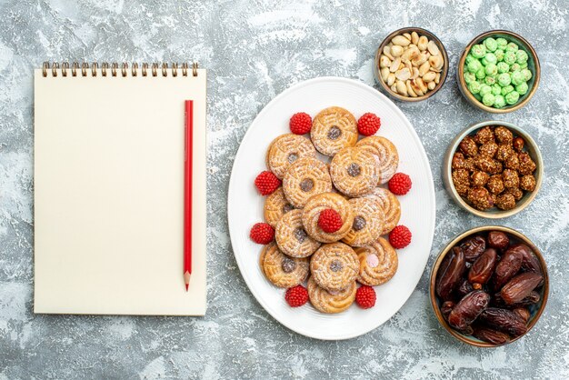 Vue de dessus des biscuits sucrés avec des bonbons et des confitures sur fond blanc clair cookies biscuits au sucre gâteau sucré thé