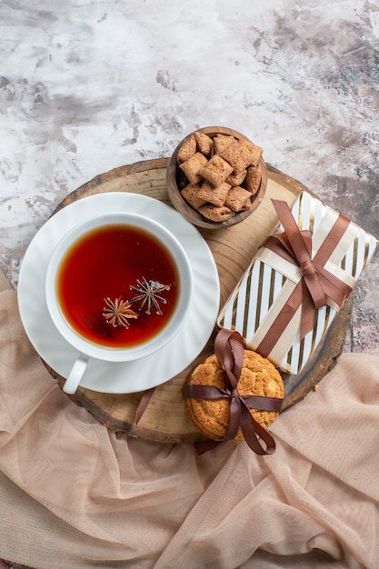 Vue de dessus des biscuits sucrés avec cadeau et tasse de thé sur la table lumineuse