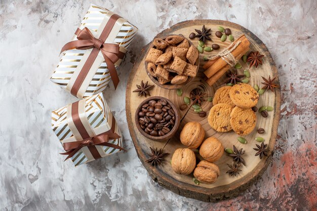 Vue de dessus des biscuits sucrés avec des cadeaux et des noix sur une table lumineuse