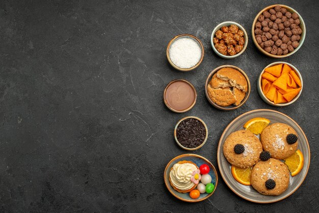 Vue de dessus des biscuits sucrés avec des frites et des tranches d'orange sur une surface sombre biscuit aux biscuits fruti gâteau à la tarte sucrée