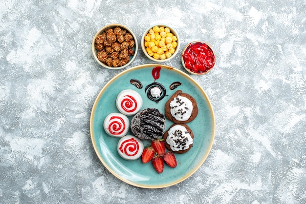 Vue de dessus biscuits sucrés avec gâteau au chocolat et bonbons sur fond blanc bonbon sucre biscuit gâteau thé sucré