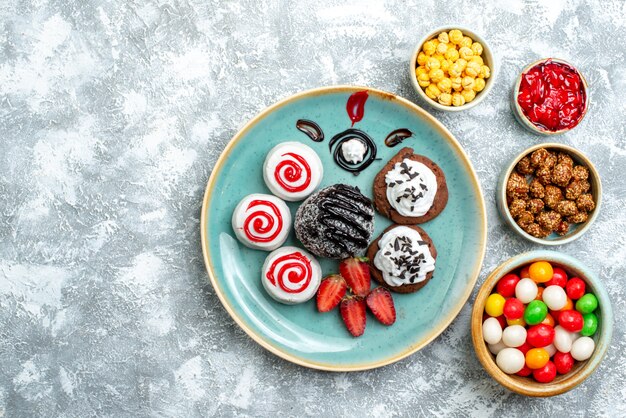 Vue de dessus biscuits sucrés avec gâteau au chocolat et bonbons sur fond blanc bonbon sucre biscuit gâteau thé sucré