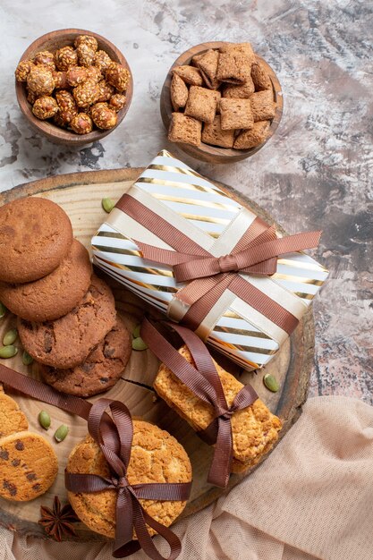 Vue de dessus des biscuits sucrés avec des noix et des cadeaux sur une table lumineuse