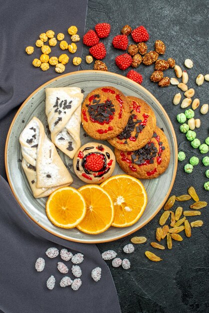 Vue de dessus des biscuits sucrés avec des pâtisseries et de l'orange sur une surface grise biscuit aux fruits biscuit sucré