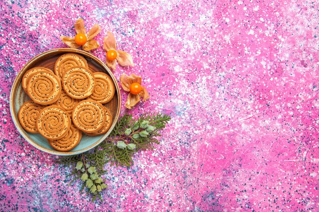 Vue de dessus de biscuits sucrés avec physalises sur surface rose clair