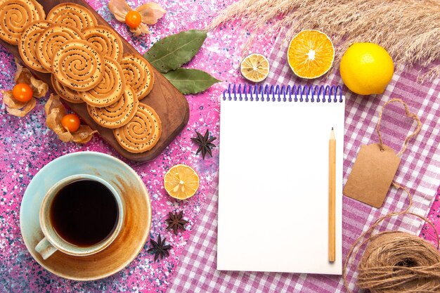 Vue de dessus des biscuits sucrés ronds avec tasse de thé et de citron sur la surface rose