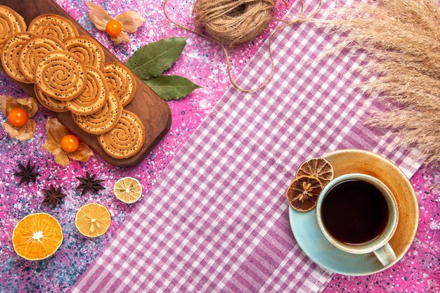 Vue de dessus des biscuits sucrés ronds avec tasse de thé sur la surface rose