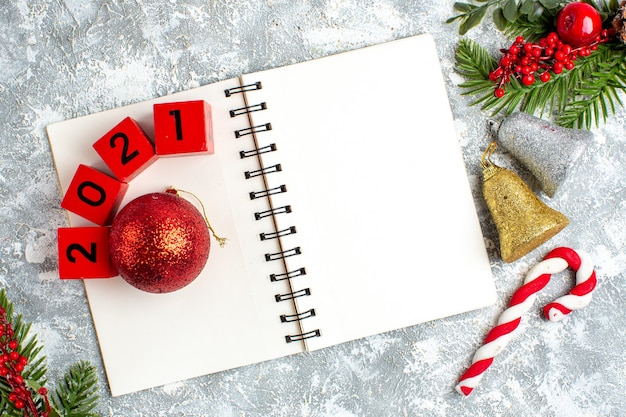 Photo gratuite vue de dessus des blocs de bois de jouet d'arbre de noël sur les cloches de noël du bloc-notes sur une table blanche grise