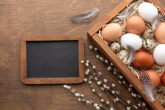 Vue de dessus de la boîte avec des oeufs pour Pâques et tableau noir