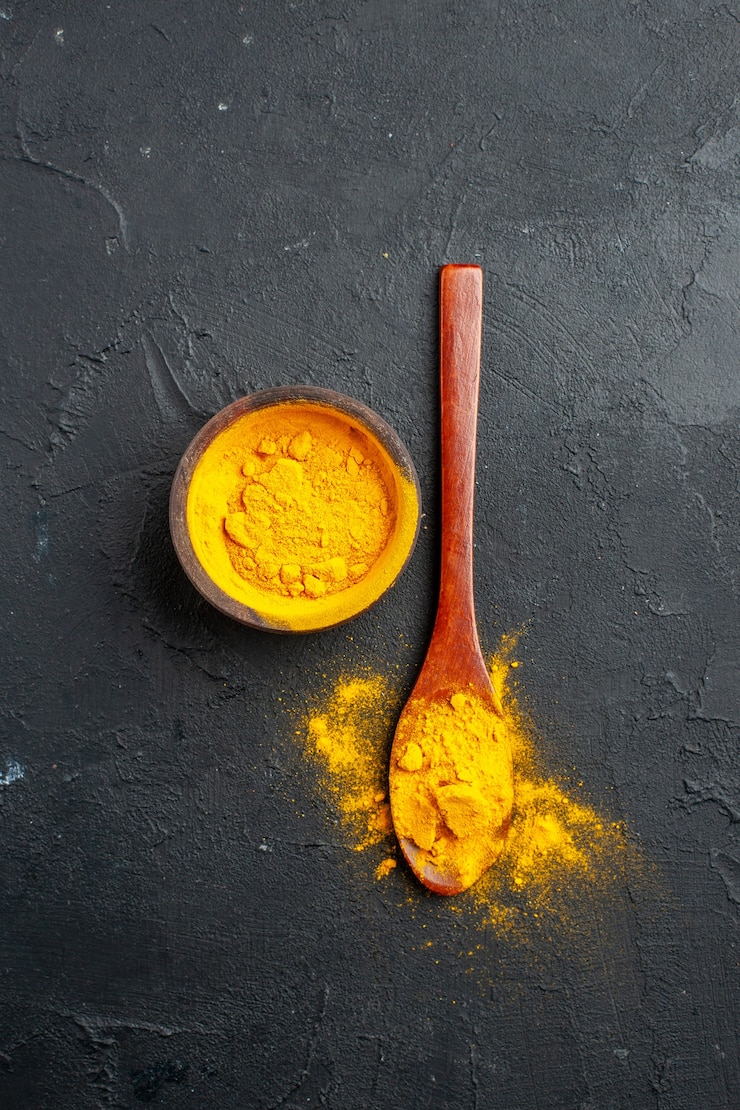 Photo gratuit vue de dessus bol de curcuma curcuma dans une cuillère en bois sur place libre de table sombre