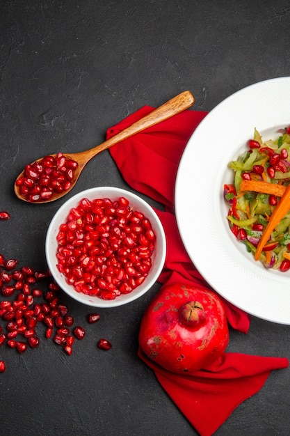 Vue de dessus bol de grenade de graines de salade de légumes grenade nappe rouge