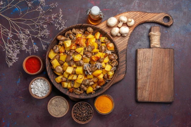 Photo gratuite vue de dessus bol avec pommes de terre et champignons bol avec pommes de terre et champignons champignons blancs huile en bouteille épices colorées et une planche à découper