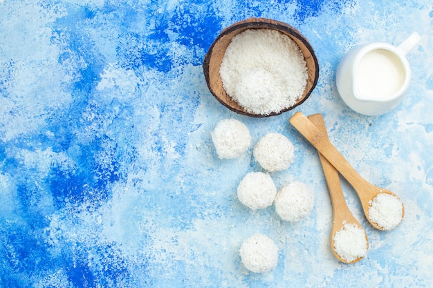 Vue de dessus bol de poudre de noix de coco et boules de noix de coco sur fond blanc bleu