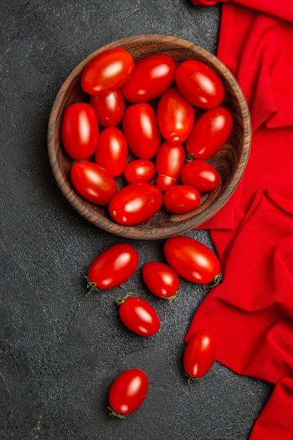 Vue de dessus bol avec serviette rouge tomates cerises et tomates cerises sur fond sombre